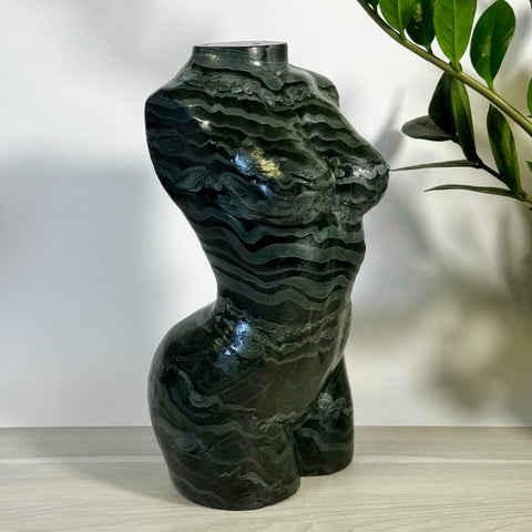 Green banded goddess body statue with wavy dark and light green patterns.