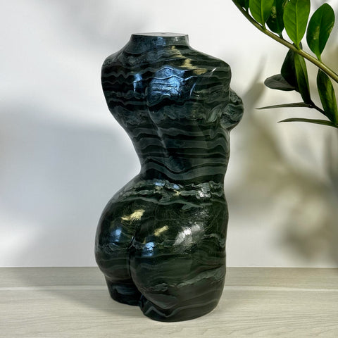 Green banded goddess body statue with wavy dark and light green patterns.