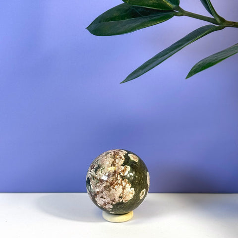 Green Cherry Blossom Sphere with white and pink floral patterns on a stand, against a purple background.