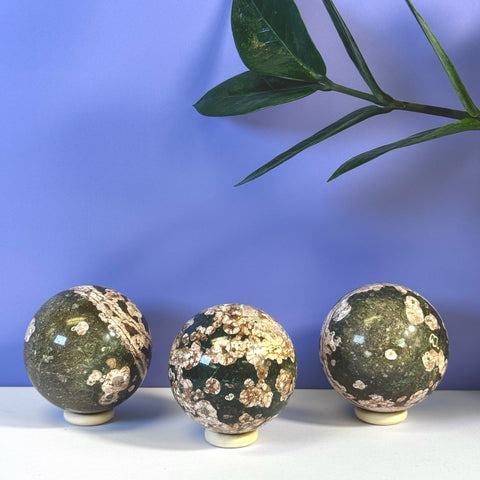Three dark green Cherry Blossom Spheres with pink and white floral patterns on stands.