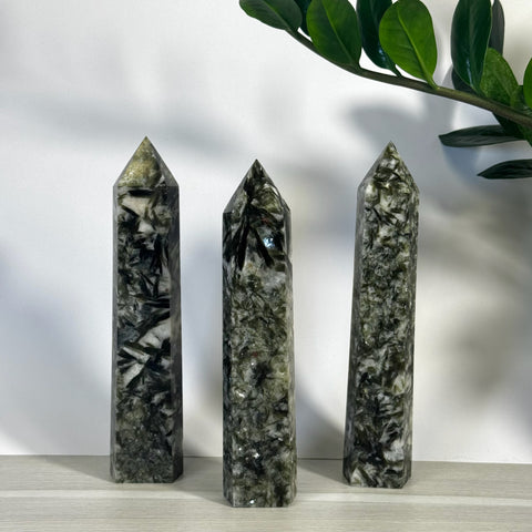 Three polished green mica crystal towers with dark inclusions, standing upright.
