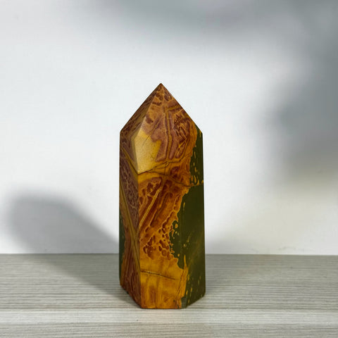 Polished realgar tower with natural red, orange, yellow, and green earthy patterns.