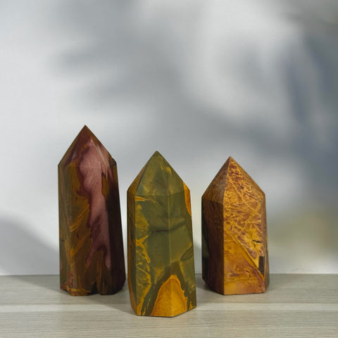 Three imperfect realgar towers, each a unique blend of earthy red, green, and yellow hues.