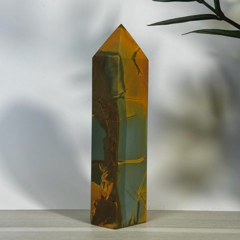 Tall, polished realgar tower with natural gold, green, and brown striations, tapering to a point.