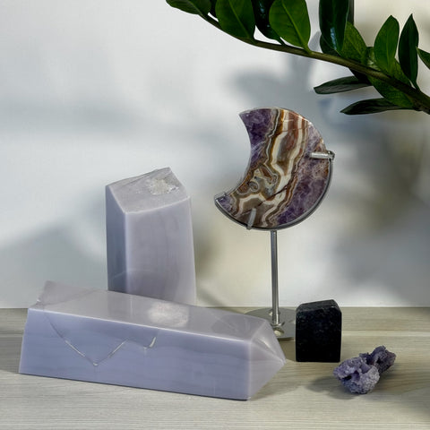 Lavender calcite towers, a crescent-shaped amethyst agate, and small black and purple crystals.