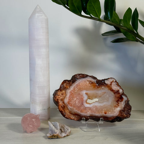 Pink calcite tower, rose quartz pig, amethyst cluster, and a large pink geode on a clear stand.