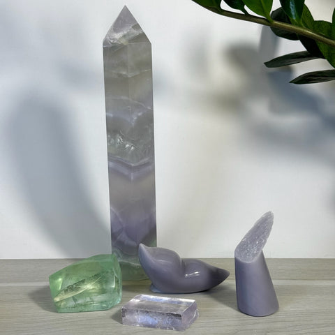 Lavender fluorite tower, green fluorite chunk, and two purple whale tail carvings with a rectangular crystal.