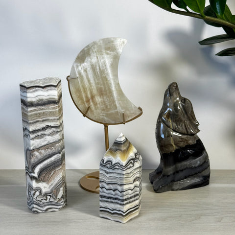 Polished black and white zebra calcite crystal tower, moon, and wolf carvings.