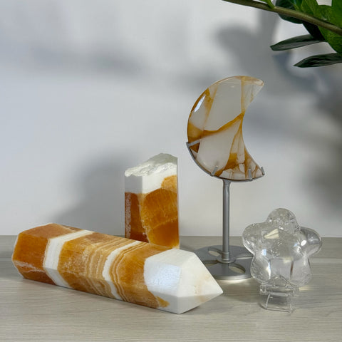 Orange and white crystal bundles: a faceted wand, a rough-top tower, a crescent moon, and a clear figure.