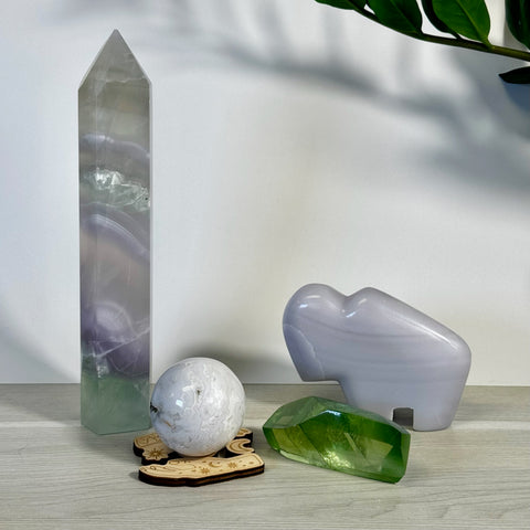 Kenna's Stylized Imperfect Bundle: tall purple-green crystal tower, white patterned sphere on wood, green crystal, and a grey elephant-shaped crystal.