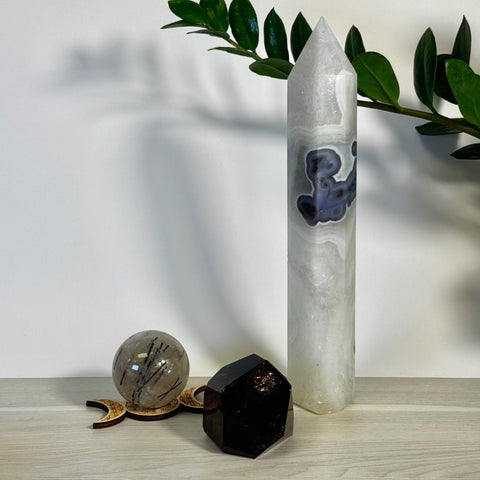 Kenna's Stylized Imperfect Bundle: Tall white crystal tower with purple inclusions, smoky quartz sphere on wood stand, and dark crystal.