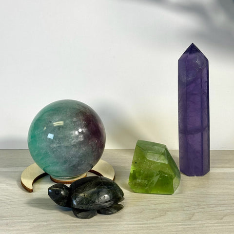 Kenna's Stylized Imperfect Bundle: green-purple crystal sphere on wood stand, dark turtle, green crystal, and tall purple crystal.
