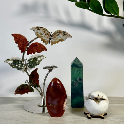Stylized crystal butterfly tree, deep red agate, green fluorite tower, and white geode sphere.