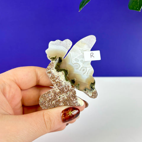 Handheld kneeling fairy princess carving made of scenic moss agate with intricate white banding and earthy green inclusions.