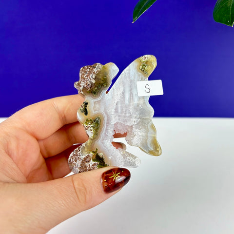 Small kneeling fairy carving hand-cut from scenic moss agate with natural green inclusions and crystalline details.