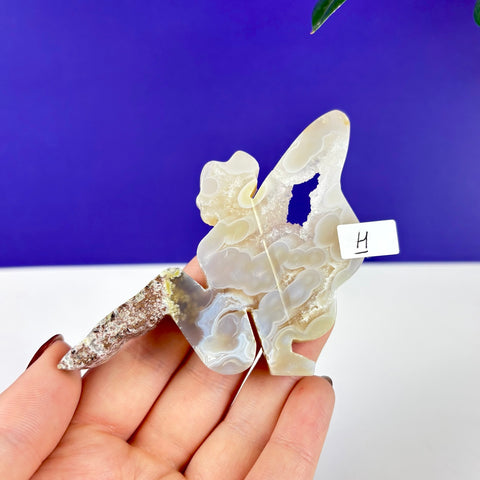 Hand-carved lounging fairy princess figurine made of translucent, patterned scenic moss agate held in a palm.