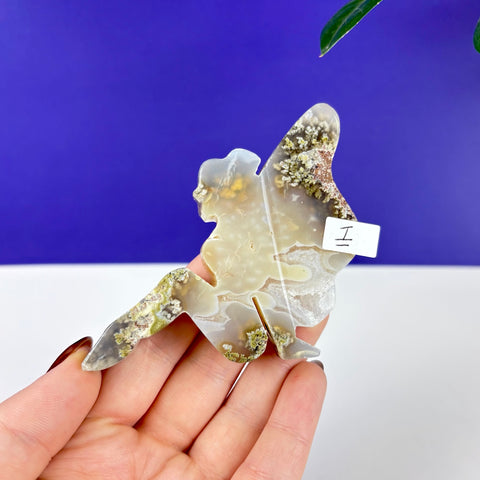 Handheld fairy-shaped carving made of translucent scenic moss agate with green mossy inclusions and white banding.
