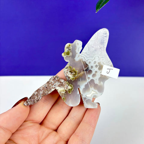 Hand-carved moss agate lounging fairy princess figurine with intricate white and grey floral patterns and green moss inclusions.