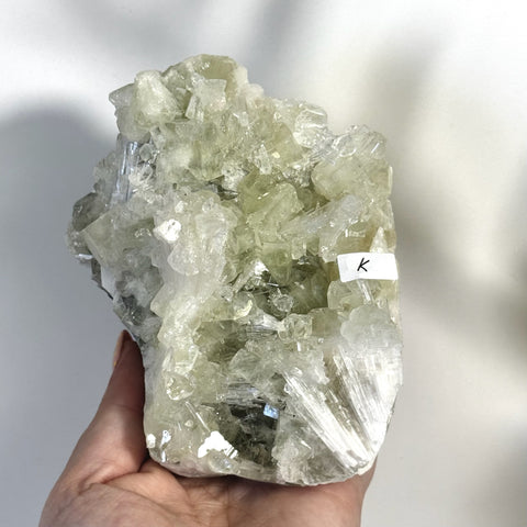 Hand holding a large, sparkling minty green Apophyllite with white Scolecite crystal cluster, variant K.