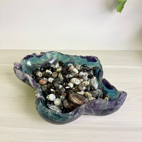Mystic Mountain bowl carved from purple and green fluorite filled with a collection of polished gemstone pebbles.
