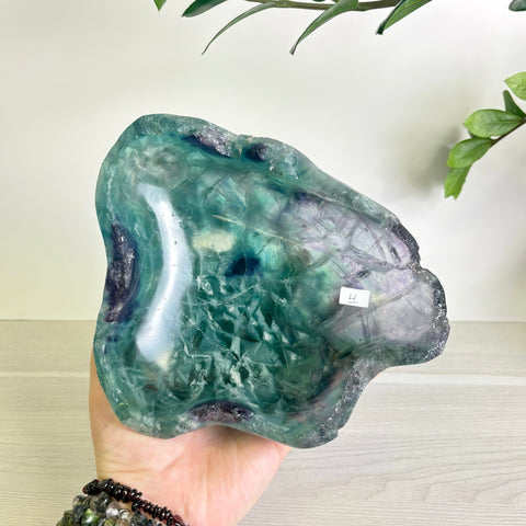 Hand-carved fluorite bowl featuring natural green and purple crystalline patterns with a polished, organic shape.
