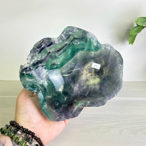 Handheld Mystic Mountain bowl carved from polished fluorite with vibrant green and purple banded mineral patterns.