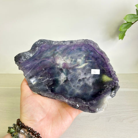 Handheld Mystic Mountain fluorite bowl featuring deep purple and green swirling crystal patterns with a raw, polished edge.