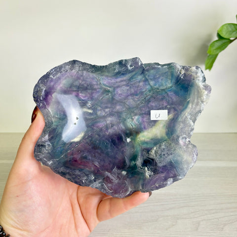 Handheld polished fluorite bowl featuring swirling purple, blue, and green crystalline patterns with a raw, natural edge.