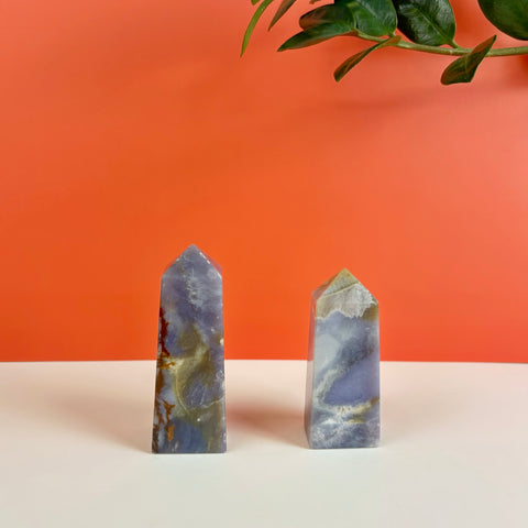 Two polished Nightshade Chalcedony crystal towers featuring purple, grey, and earthy brown mineral patterns.