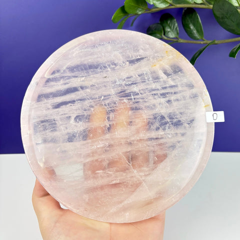 Handheld round rose quartz crystal plate with natural translucent pink veining and a polished finish.