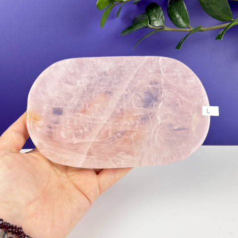 Handheld oval-shaped rose quartz crystal plate with a smooth, polished finish and natural crystalline texture.