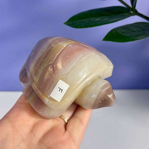 Pink banded onyx turtle figurine, variant F, held in a hand.