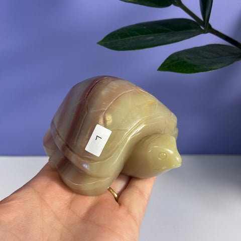 Pink banded onyx turtle carving, L variant, held in a hand.