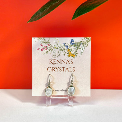 Silver drop earrings with oval rainbow moonstone cabochons on a "Kenna's Crystals" card.