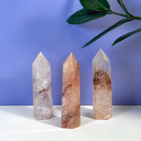 Three faceted Rainbow Pink Fire Azeztulite crystal towers with natural reddish inclusions.