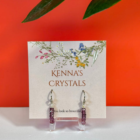 Donut-shaped rhodolite garnet earrings with silver hooks on a floral Kenna's Crystals card.