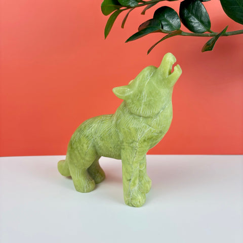 Hand-carved light green serpentine stone wolf figurine howling, featuring natural veining and a smooth polished finish.