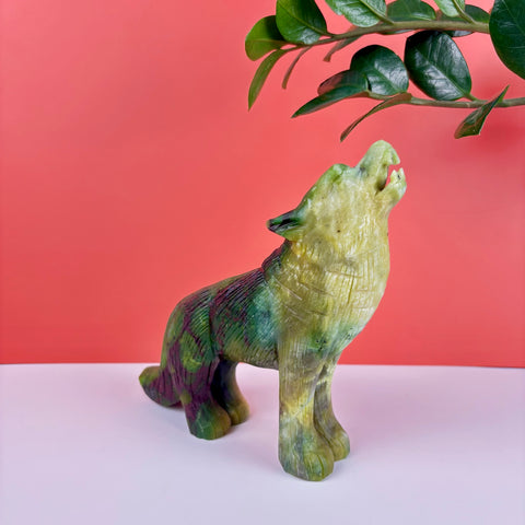 Hand-carved serpentine stone wolf figurine in shades of green and purple, depicted in a howling pose.