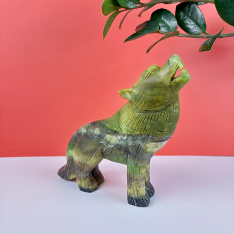Hand-carved green serpentine stone wolf figurine howling, featuring natural mineral patterns and detailed fur texture.