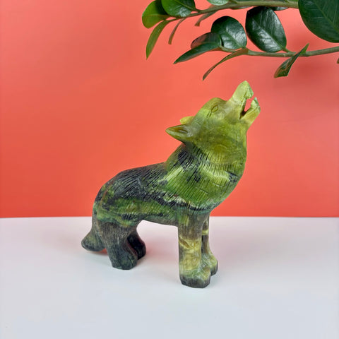 Hand-carved serpentine stone wolf figurine in shades of green and black, depicted in a howling pose.