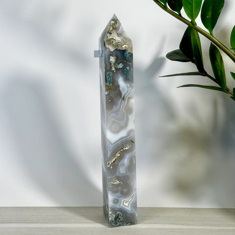 Tall, polished moss agate tower with white, grey, and green natural patterns, standing upright.