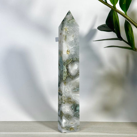 Tall, polished moss agate crystal tower with white, green, and brown natural patterns.