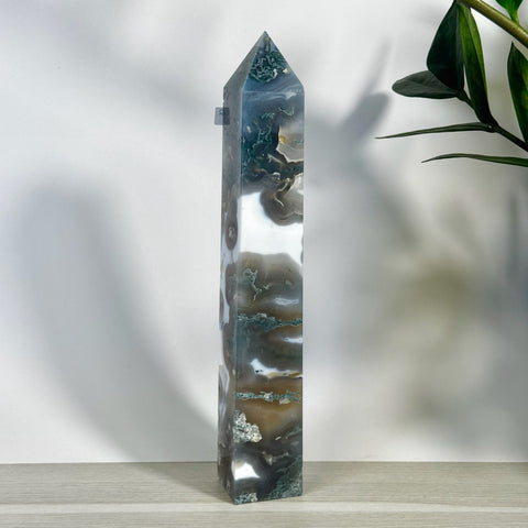 Tall, polished moss agate tower with white, green, and brown swirling patterns, standing on a light wooden surface.