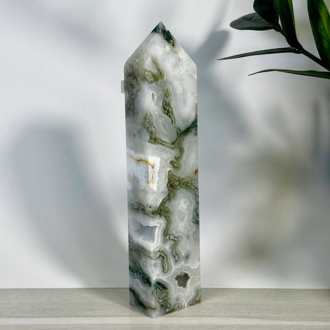 Tall, polished moss agate tower with white, clear, and green patterns, featuring natural geode inclusions.