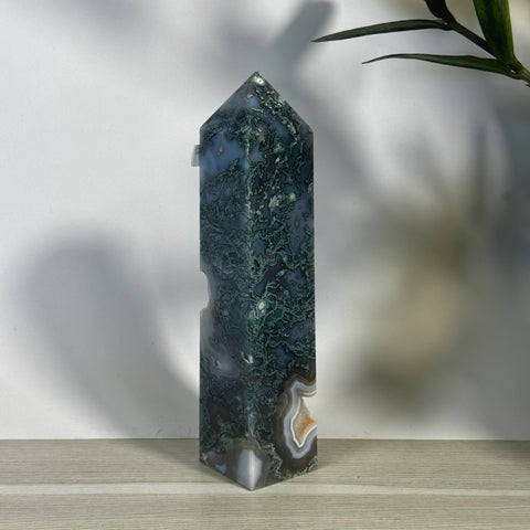 Tall, polished moss agate tower with deep green inclusions and white, gray, and brown banding.