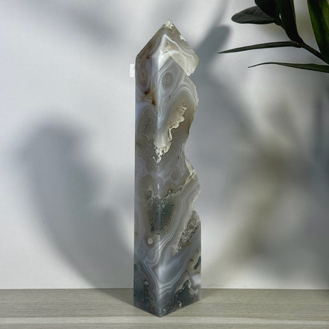 Tall, polished moss agate tower with natural grey, white, and brown swirling patterns and raw crystal edges.