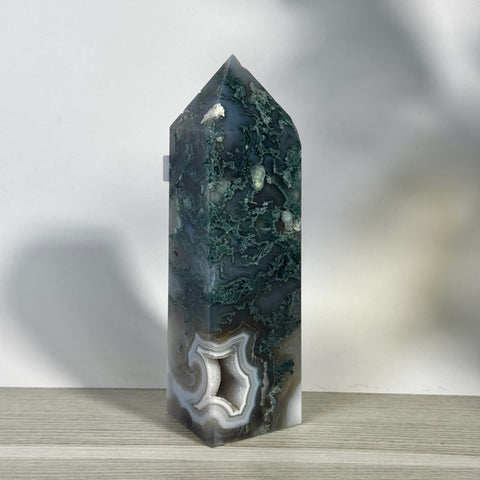 Tall, polished moss agate tower with deep green and white patterns, featuring a small geode opening at the base.