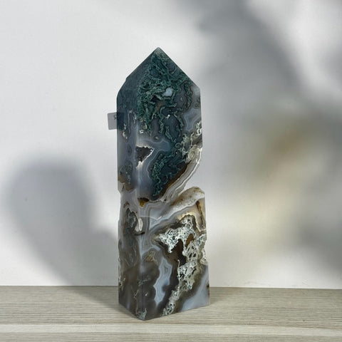 Tall, polished moss agate tower with deep green, white, and gray swirling patterns, featuring a natural geode cavity.