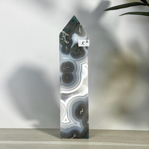 K2 Statement Moss Agate Tower, a tall, polished crystal with swirling grey, white, and green patterns.