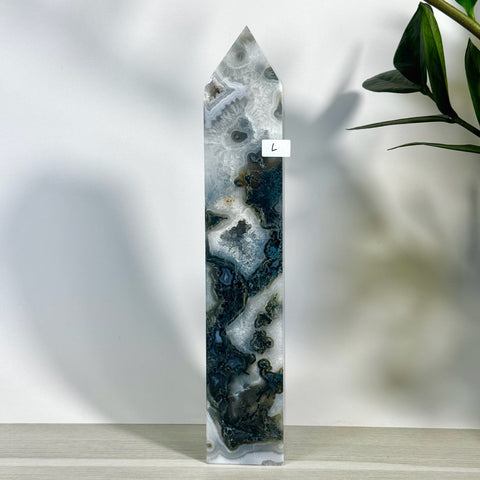 Large moss agate tower with intricate white, grey, and dark green patterns, pointed top.